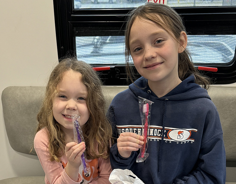 Girls smiling holding their new toothbrushes.